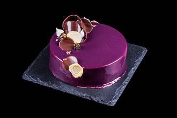  Beautiful delicious holiday cake in purple glaze. Black background.