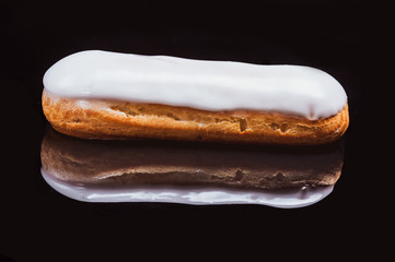 Choux cake in white icing. Black background. Close-up.