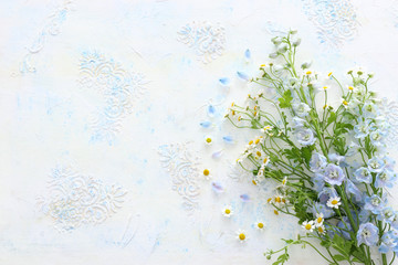 spring bouquet of white and blue flowers over white vintage wooden background. top view, flat lay