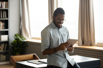 Smiling businessman web surfing information at home on digital tablet.
