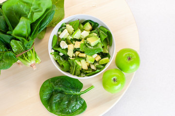 Fresh spring green vegetable salad on a table with apples and spinach on a light background. Farm...