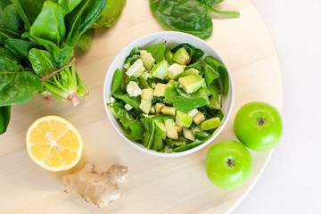 Obraz premium Fresh spring green vegetable salad on a table with apples and spinach, lemon, on a light background. Farm organic product, home-made