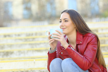 Relaxed woman enjoying cup of coffee on stairs