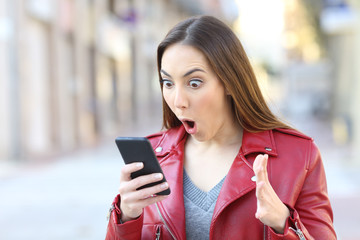 Surprised woman with mouth open looking at her phone