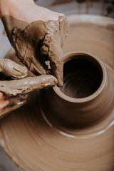 Woman hands working on pottery wheel and making a pot. - obrazy, fototapety, plakaty