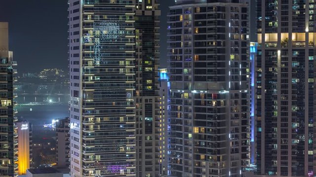 View of various skyscrapers and towers in Dubai Marina from above aerial night timelapse. Illuminated modern buildings in urban skyline