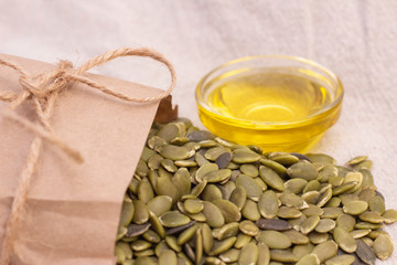 pumpkin seeds in a paper bag, pumpkin seed oil on natural linen. pumpkin seeds vitamins of group B and magnesium.