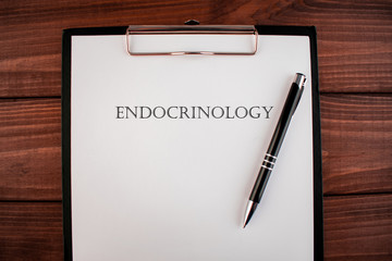 Word endocrinology: text written on a shit of paper of notebook on the wooden background. Medical concept.