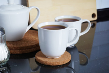 Fototapeta premium Kitchen interier. Brewed tea in white mugs on the kitchen table. Comfort and warmth at home. Tea party