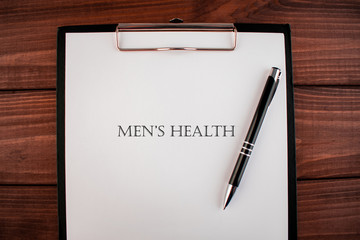 Words Men's health: text written on a shit of paper of notebook on the wooden background. Medical...