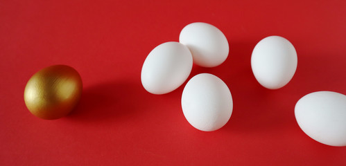 Golden and white eggs lie on a red background. Happy easter concept, top view, banner.