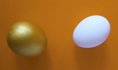 Golden and white eggs lie on a orange background. Happy easter concept, top view.
