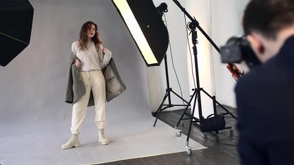 Young beautiful female model posing for a professional photographer during a photo shoot in the studio.