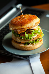 Eating at work place - fast food. burger near laptop. lunch break while you work or sharing online
