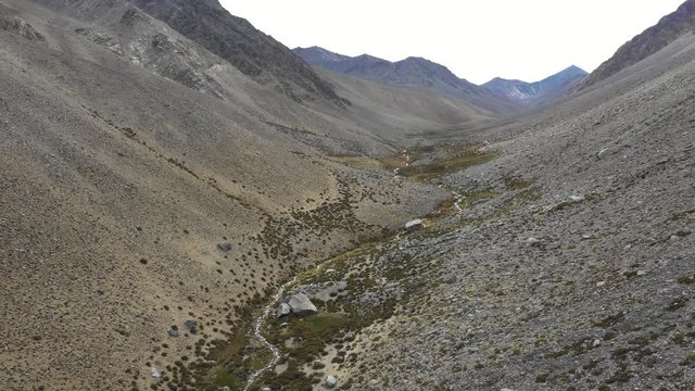 A reverse flight view inside Andes mountains at Limari Valley, south Atacama. An amazing wild scenery. Arid idyllic valleys with green farm fields feed in by the river at the bottom of the valley
