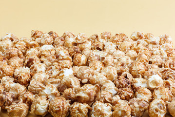 Heap of delicious caramel popcorn, isolated on yellow background . Scattered popcorn texture background.
