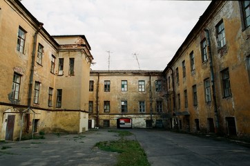 Fototapeta na wymiar Sullen cityscape. Empty yard with abandoned old brick houses in rainy day Saint-Petersburg, Russia
