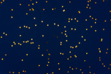 Classic blue abstract background. Festive holiday background for your projects. Color of the year 2020 concept. Photo of confetti stars sparkles on blue backdrop. Top view, flat lay
