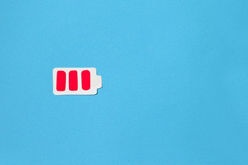 Battery low concept. Battery paper figure and red blocks with copyspace, top view, flat lay. on a blue background