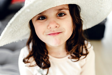 girl in a hat,young little beautiful girl in a hat looks at the camera,happy young girl smiling,looking a little girl at the camera,brown eyes of a little girl,smile, happiness, joy