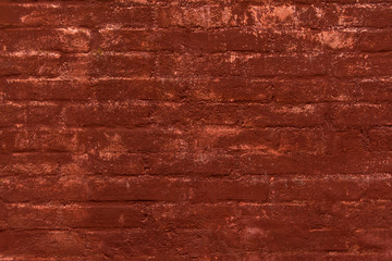 Brick wall painted in terracotta color. Traces of old paint. Wall of a very old european house. Textured surface.