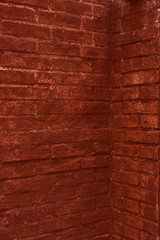 Brick wall painted in terracotta color. Traces of old paint. Wall of a very old european house. Textured surface.
