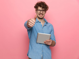 happy young guy holding tab and making thumbs up sign