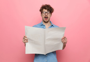 young casual guy reading news on pink background