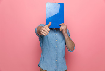 casual denim guy covering face with clipboard
