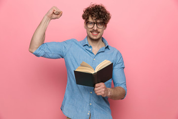 confident young guy holding book and showing muscles