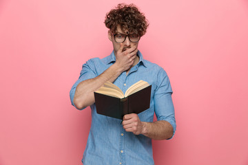 shocked guy holding hand to mouth and reading a book