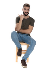 Arrogant casual man pointing behind him while sitting