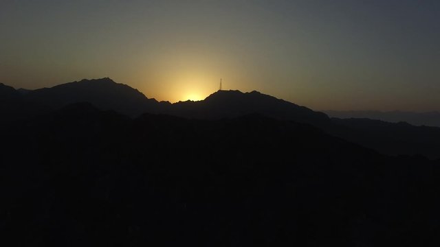 Silhouette of power line on top of mountain during sunset