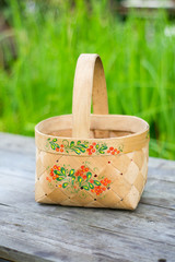 close-up russian domestic birch bast basket with Khokhloma traditional painting on it on green...