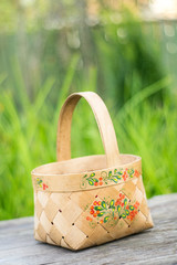 close-up russian domestic birch bast basket with Khokhloma traditional painting on it on green...