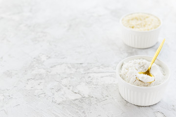 Rice flour and rice groats in white bowls on a gray table. Gluten free, healthy diet concept. Horizontal orientation, copy space.