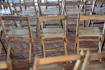 Wooden chairs are in rows on pavement.