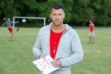 male football coach holding clipboard
