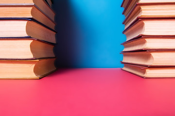 Piles of books on a pink and blue background.