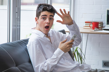 teenager or student with mobile phone at home and expression of amazement or surprise