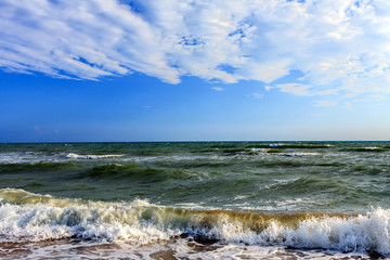 Scenic Black Sea seascape in Anapa resort in Russia. Waves splashing on sandy seashore under blue sky and clouds on sunny day.