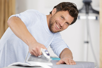 happy handsome man ironing clothes