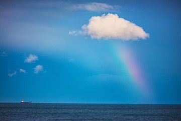 Naklejka na ściany i meble Rainbow in the sea and sailing cargo ship