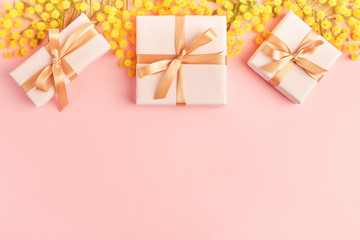 Spring flowers  mimosa with gift boxes on pink background, greeting card for Mothers Day, 8 March, Easter