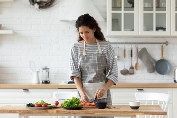 Millennial female preparing healthy lunch at home kitchen