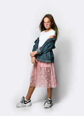 Fototapeta premium Young smiling teen girl in stylish casual clothes, sneakers and pink sunglasses standing and looking at camera