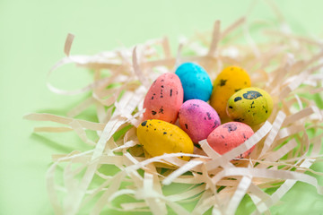 colored bright easter eggs in a nest on a green paper background. easter card
