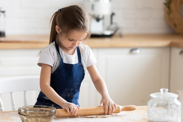 Little girl have fun baking rolling dough alone