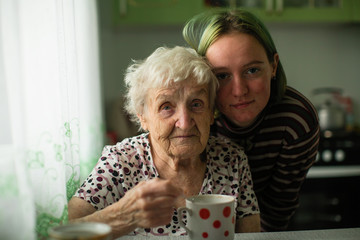 Old woman with her granddaughter in the kitchen at home.