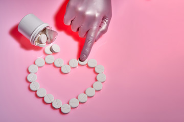 Heart sign made from white pills. Doctor points to a white pill for the heart.